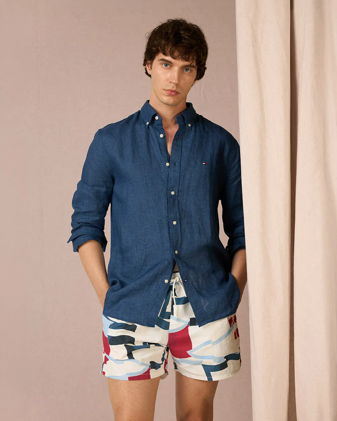 Primo piano con camicia blu scuro e costume, sfondo panna