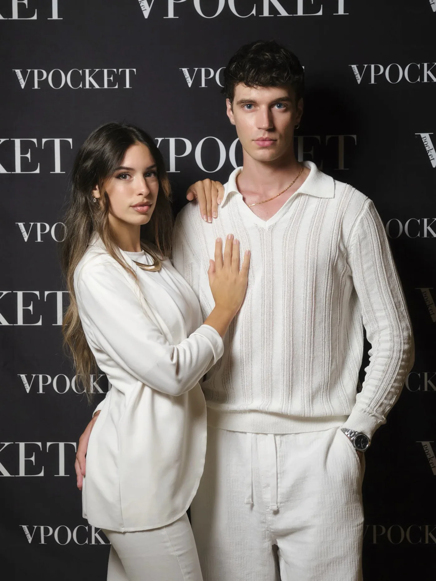 Scatto di coppia in outfit total white davanti al backdrop dell’evento VPOCKET