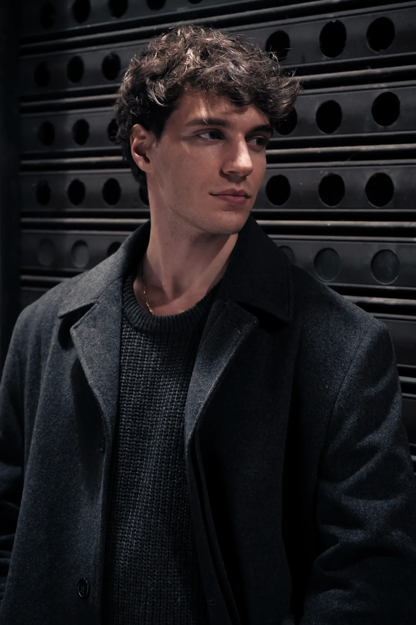 Francesco Scarparo in cappotto di lana davanti a una serranda scura