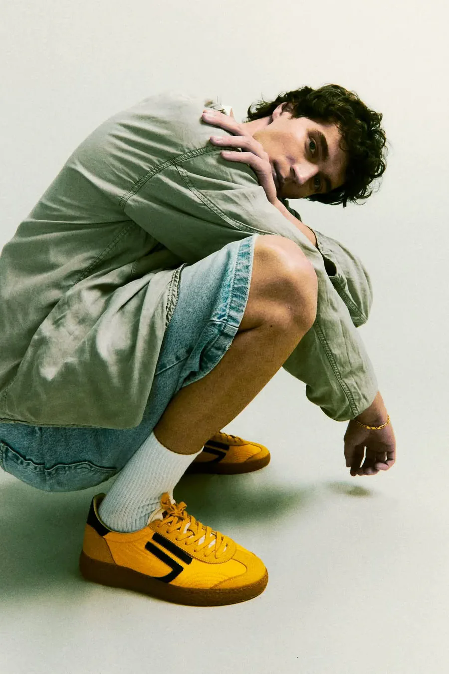 Francesco Scarparo accovacciato in studio, sneakers gialle in primo piano