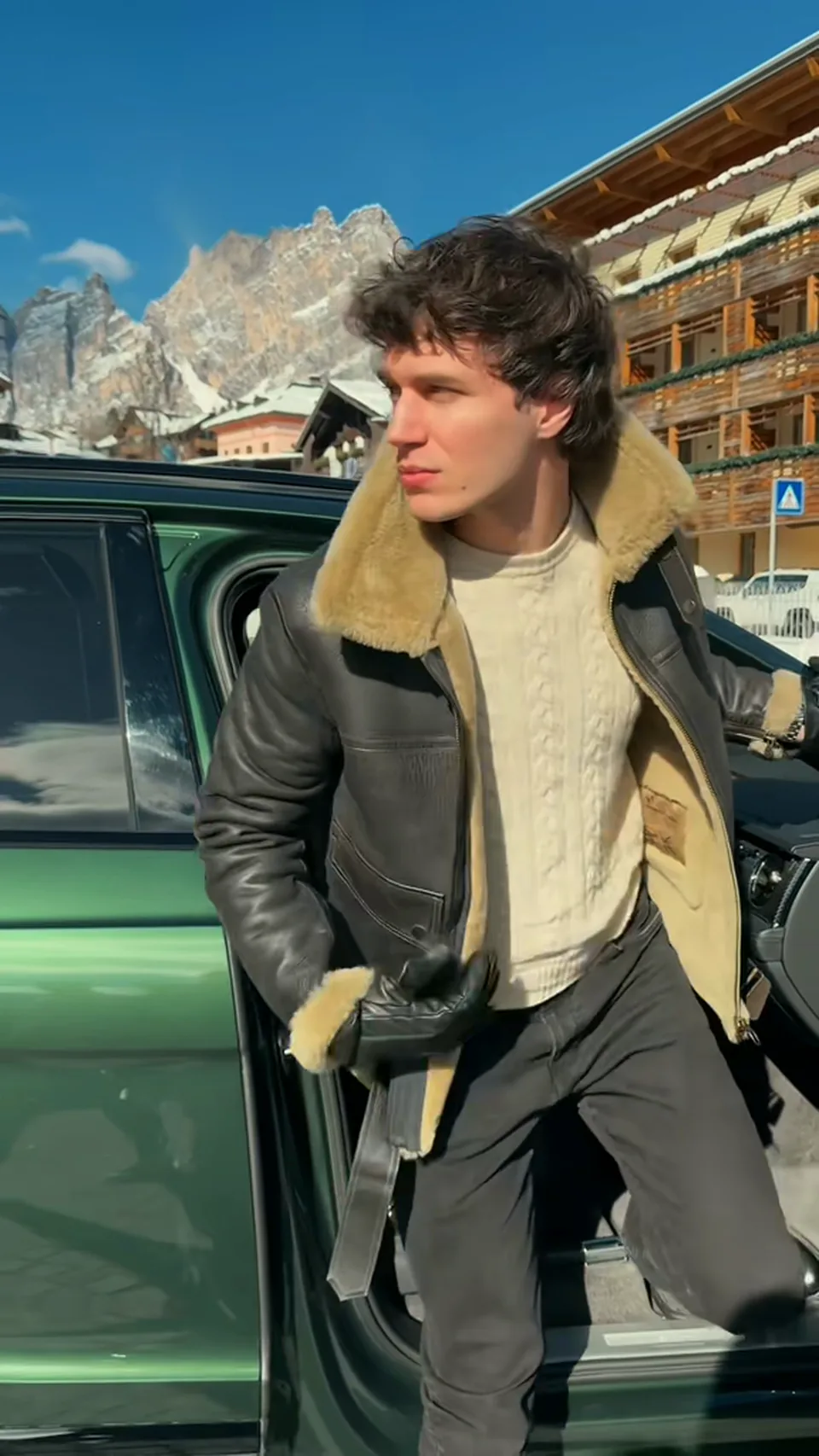 Francesco Scarparo scende da un'auto a Cortina d'Ampezzo in giacca di montone, con le Dolomiti alle spalle